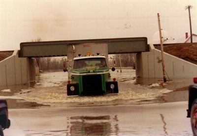Large green transport truck driving though water